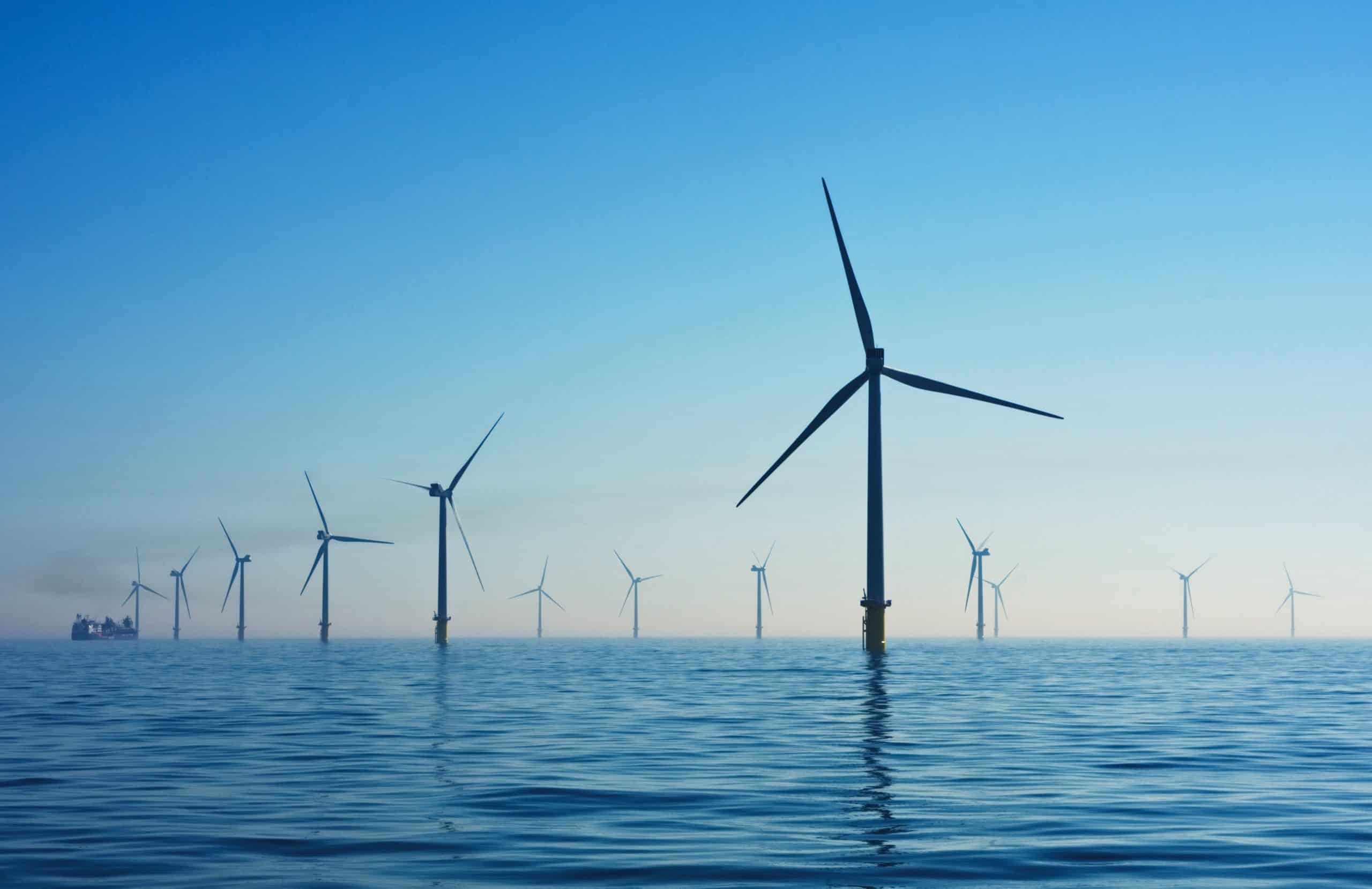 A landscape image with a view of the horizon, above the ocean. in the distance you can see wind turbines